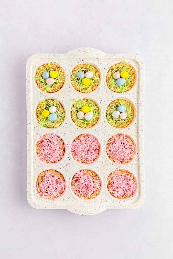 Mini muffin tray with assembled Easter Rice Krispies Nests, topped with mini Cadbury Easter eggs.
