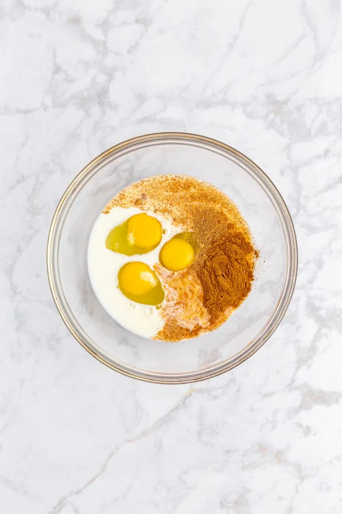 Bowl with eggs, milk, vanilla extract, nutmeg, and cinnamon.