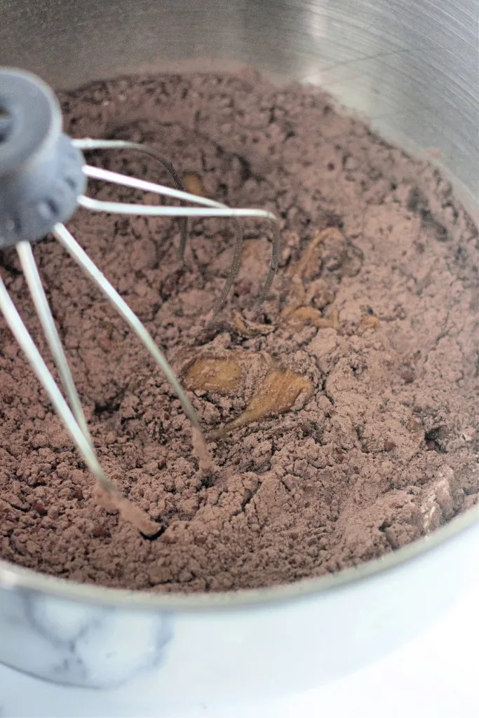 Bowl of a stand mixer with dry ingredients mixed into the wet ingredients for cosmic brownie cookies.