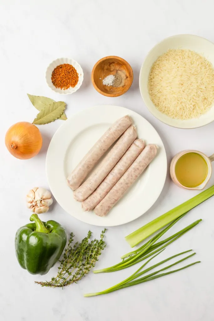 Ingredients for Dirty Rice with Sausage on a white kitchen countertop.