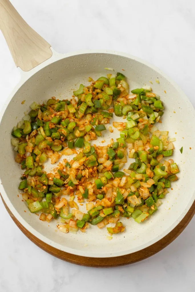 Large skillet with softened veggies and seasoning.