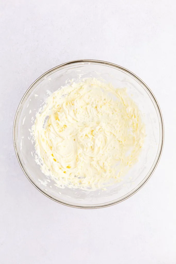 Large mixing bowl with beaten cream cheese.