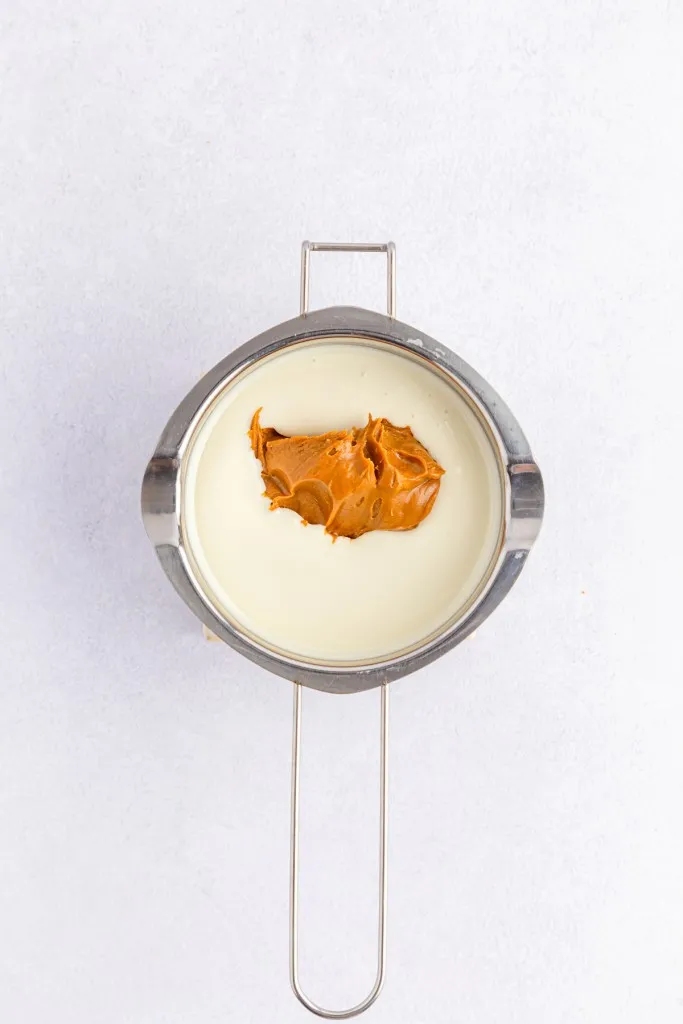 Double boiler with melted vanilla melting wafers and Biscoff cookie butter spread.