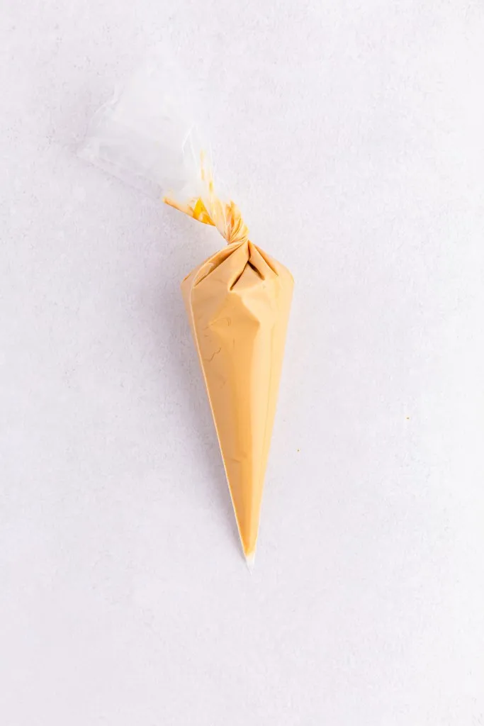 Plastic piping bag filled with melted Biscoff drizzle to decorate the assembled Biscoff truffles.