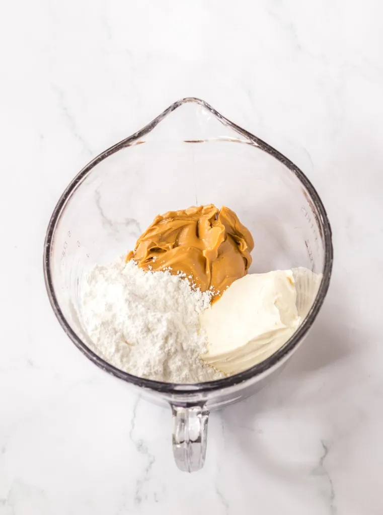 Glass bowl with peanut butter, cream cheese, and powdered sugar.