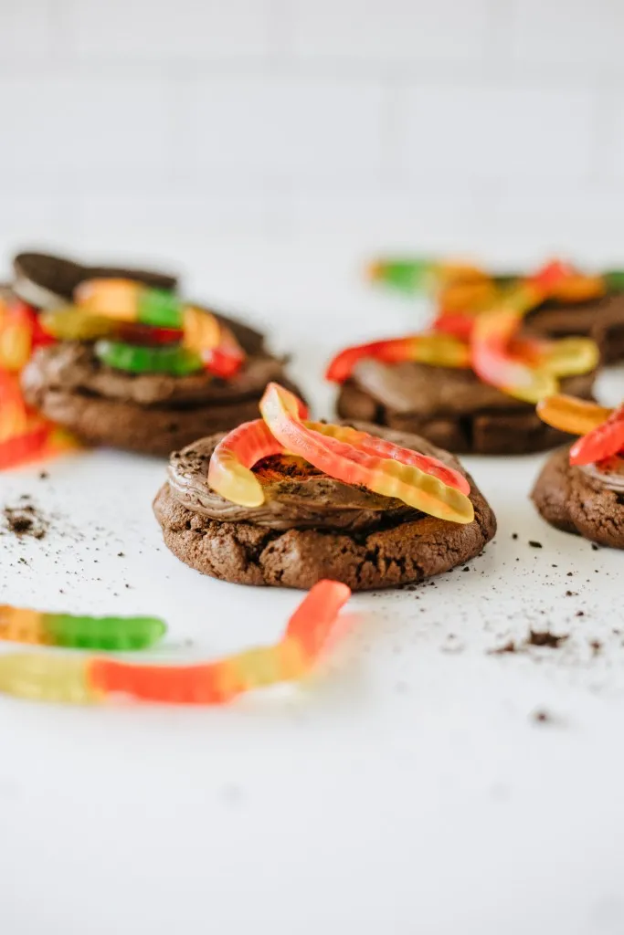 Crumbl-style dirt cake cookie topped with chocolate frosting, Oreo crumbs, and a gummy worm