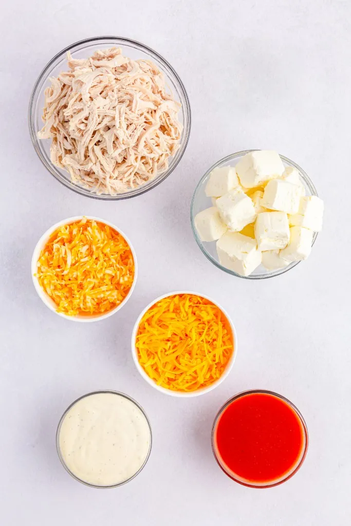 Buffalo chicken dip ingredients on a marble countertop.
