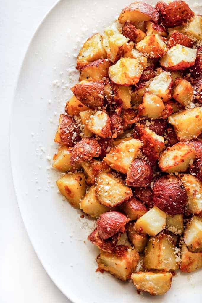 Crispy Parmesan roasted potatoes on a white platter.