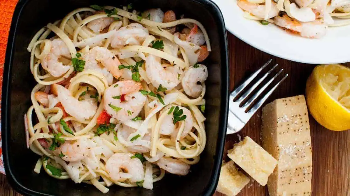 A bowl of noodles with seafood and creamy sauce.