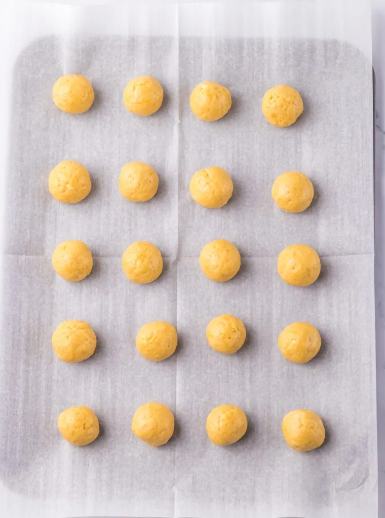 Parchment-lined tray with 1/2-inch vanilla Oreo cookie truffle balls.