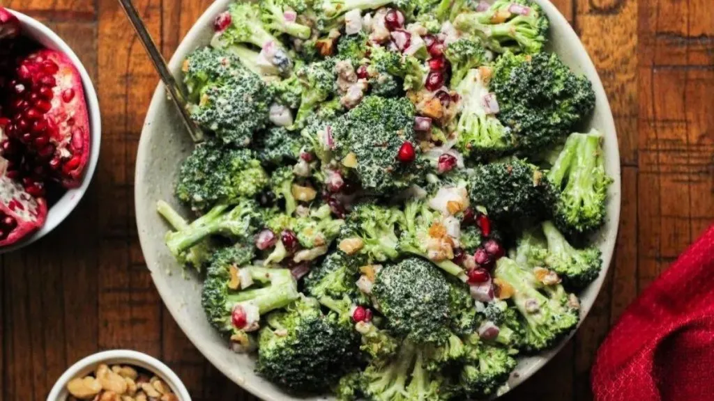 A dish of broccoli salad with pomegranate and dressing.