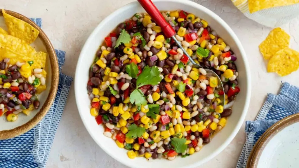 A bowl of black eyed peas and beans with dressing.