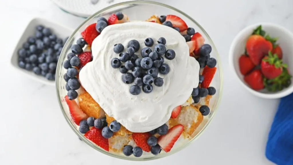 An overhead view of a summer berry trifle with cake, whipped cream and berries.