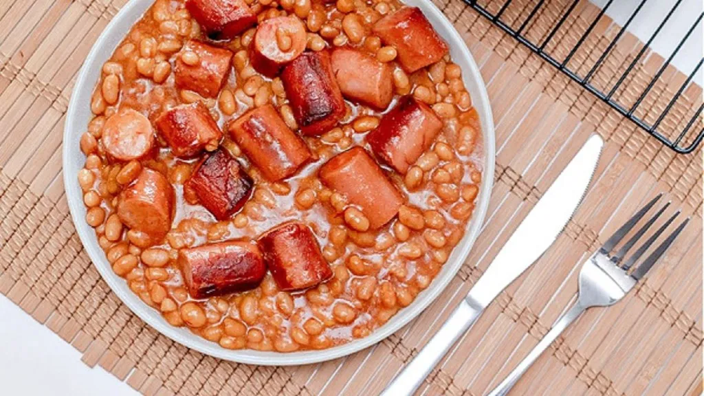 A casserole dish with baked beans and hot dog slices.