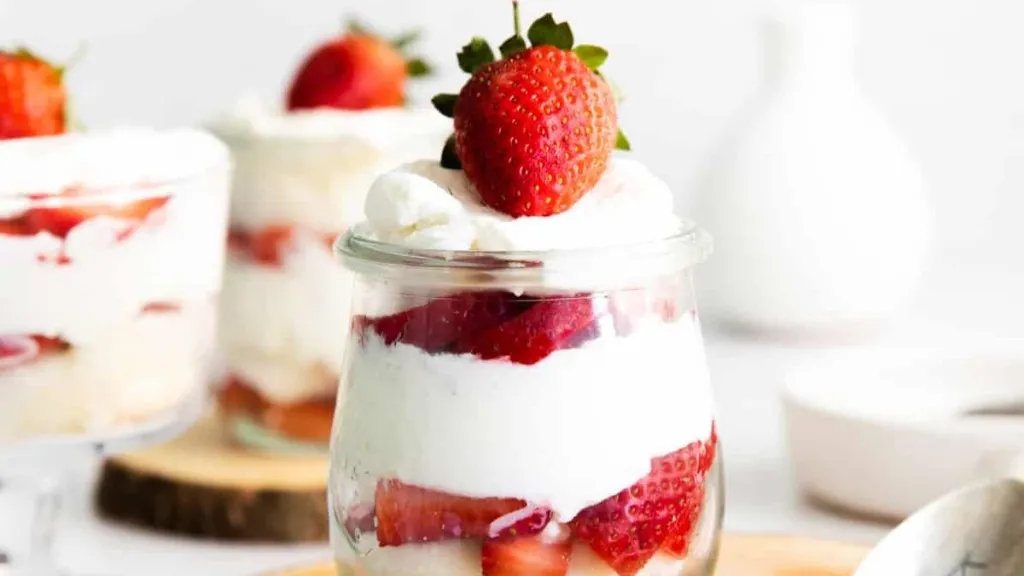 Layers of strawberry shortcake in a small jar.
