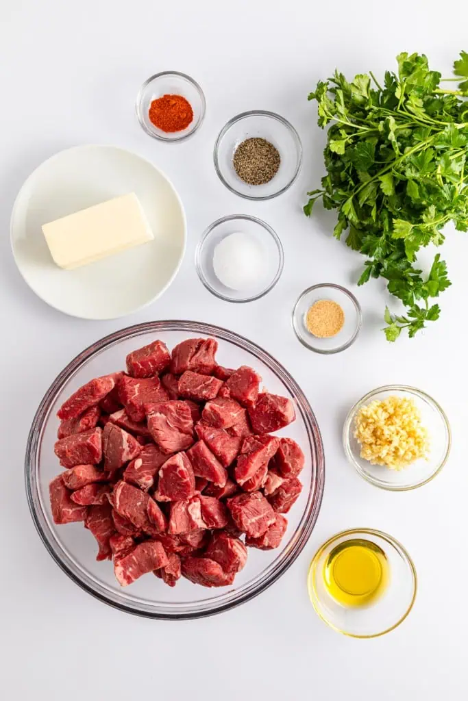 Garlic butter steak bites ingredients in separate bowls on a white countertop.