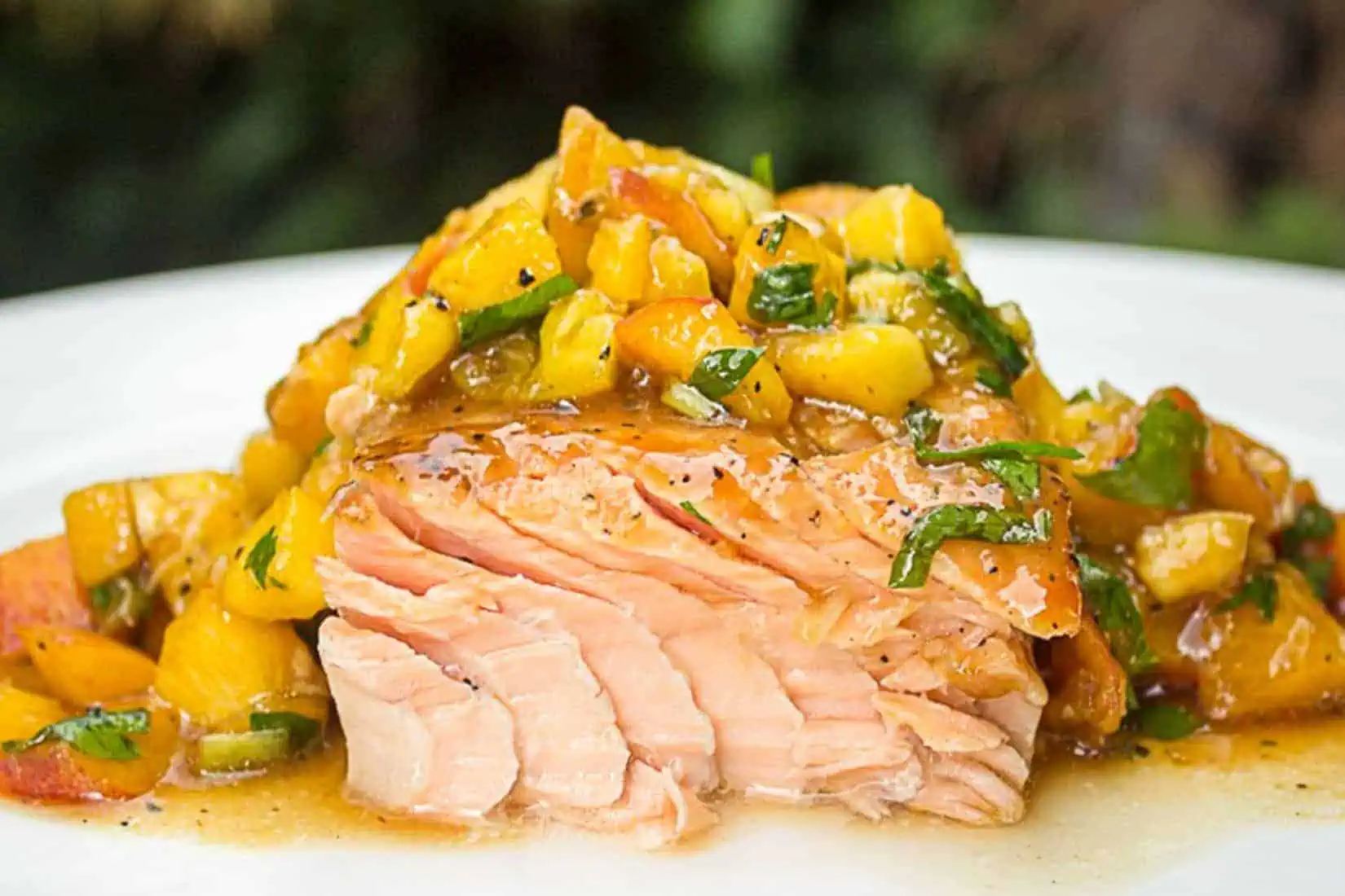 a plate of salmon with a sticky glaze over the top, with fresh peach salsa