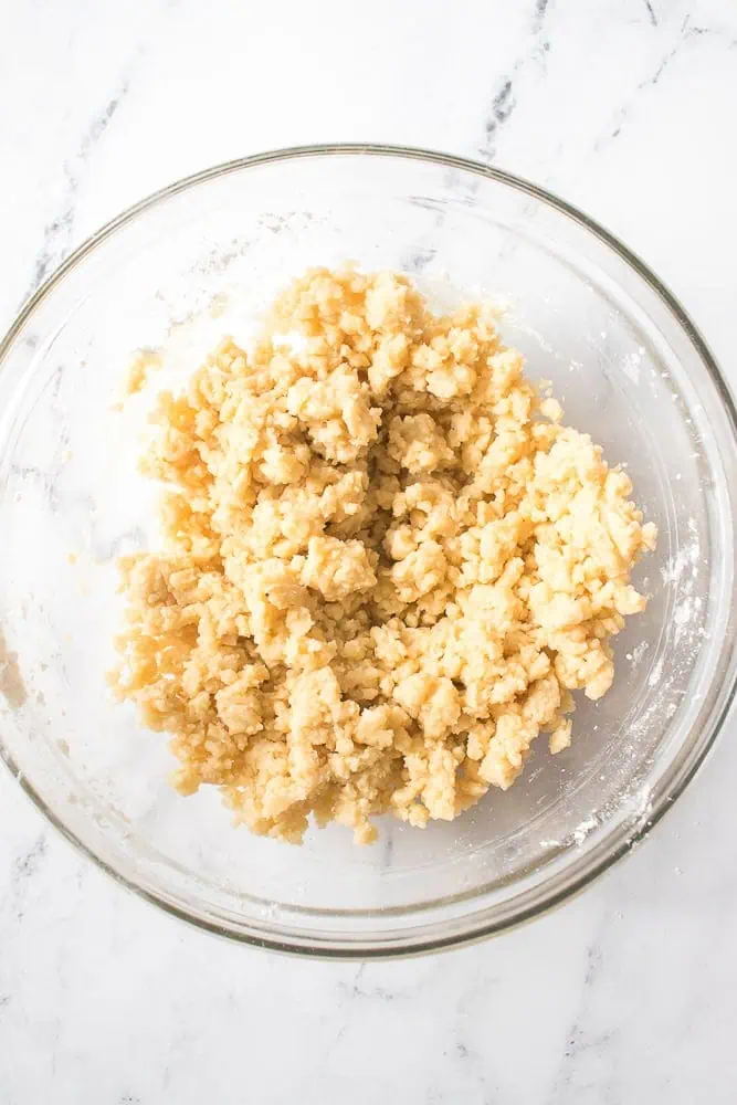 Glass mixing bowl with blended pumpkin pie dessert bar crust mixture.