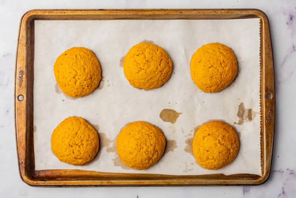 Parchment paper-lined baking tray with freshly baked pumpkin cookies.