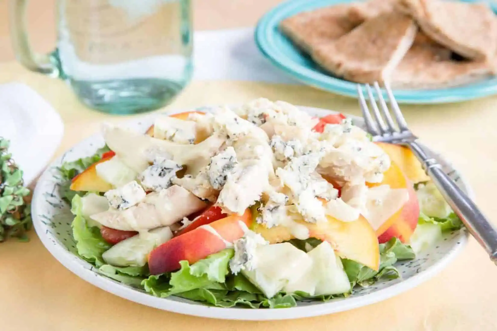 a plate of salad made of chicken, tomato, peaches and blue cheese.
