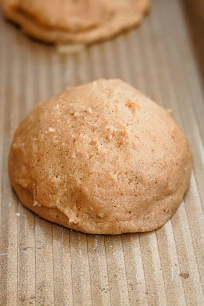 Two pumpkin cheesecake cookie dough discs crimped together to hold a dollop of the frozen cream cheese filling.