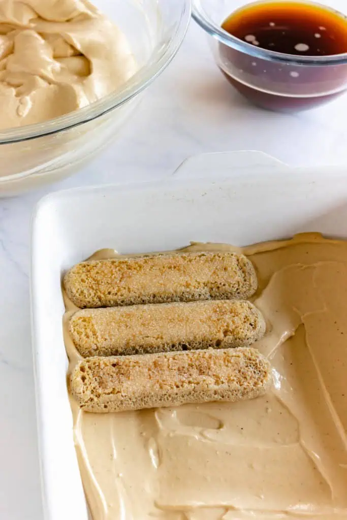 Baking pan with a layer of gingerbread mascarpone mixture and ladyfingers added on top.