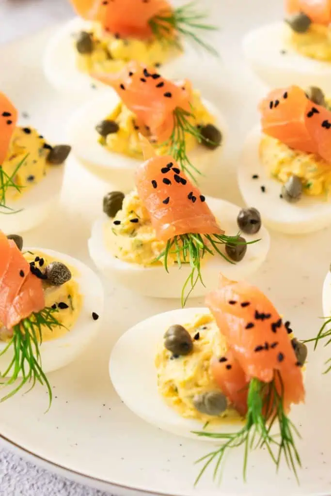 Close up of assembled smoked salmon deviled eggs on a white serving plate.