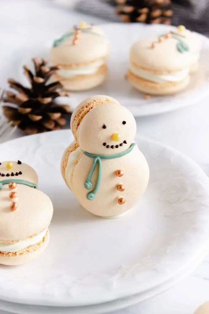 Snowman macarons on white plates with table decorations.