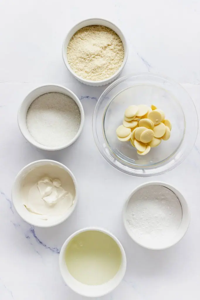 Ingredients for making snowman macarons on a marble countertop.