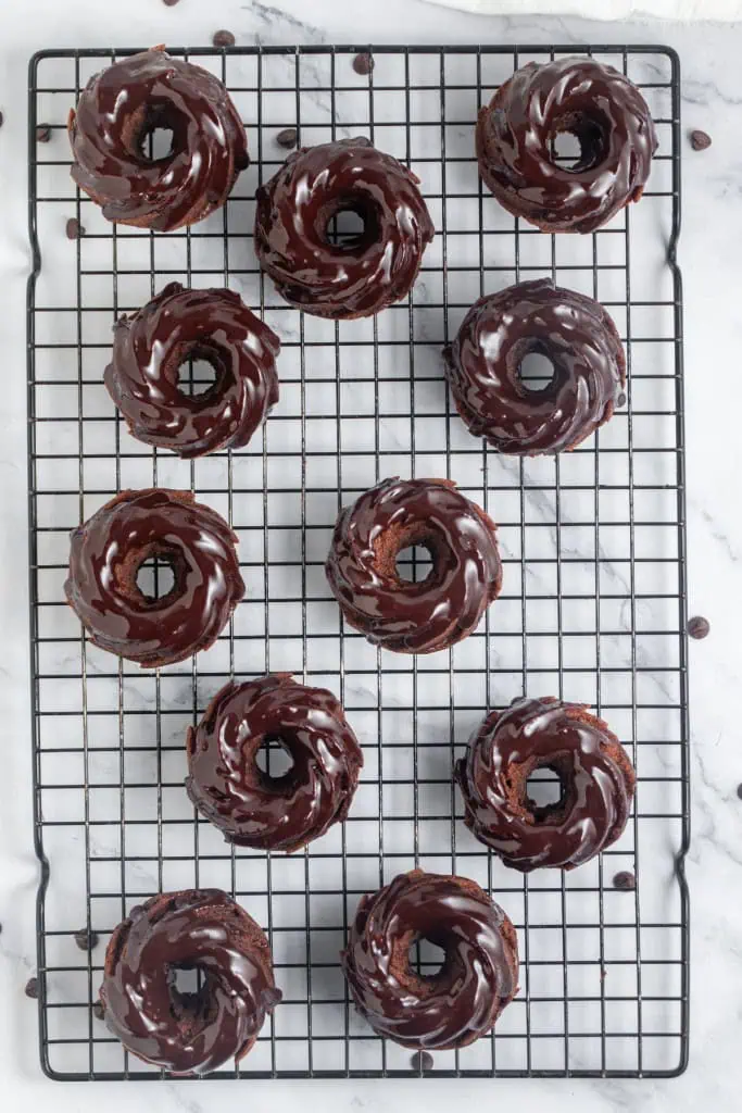 Freshly baked and cooled mini chocolate bundt cakes on a wire cooling rack, coated with a chocolate ganach topping.