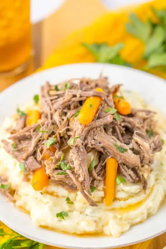 Close up of slow cooker garlic herb pot roast served over mashed potato.