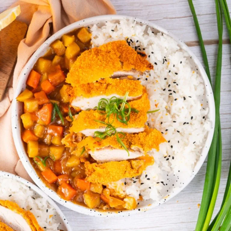 Overhead view of tender crisp pan fried pork katsu over white rice and curry