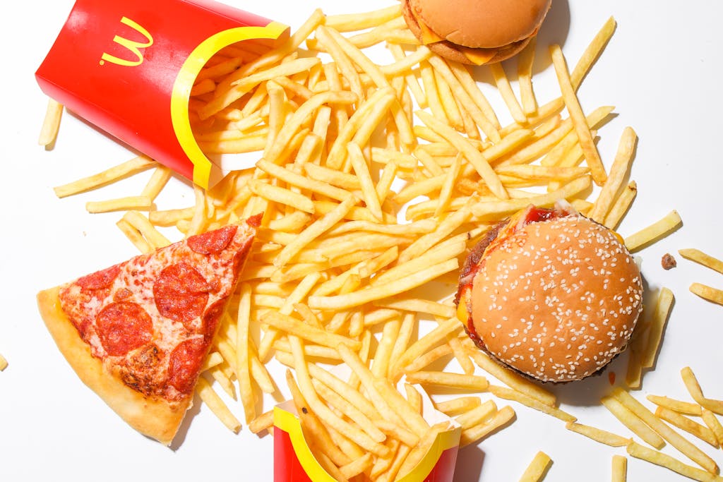 A tantalizing spread of burger, fries, and pizza showcasing classic fast food indulgence.
