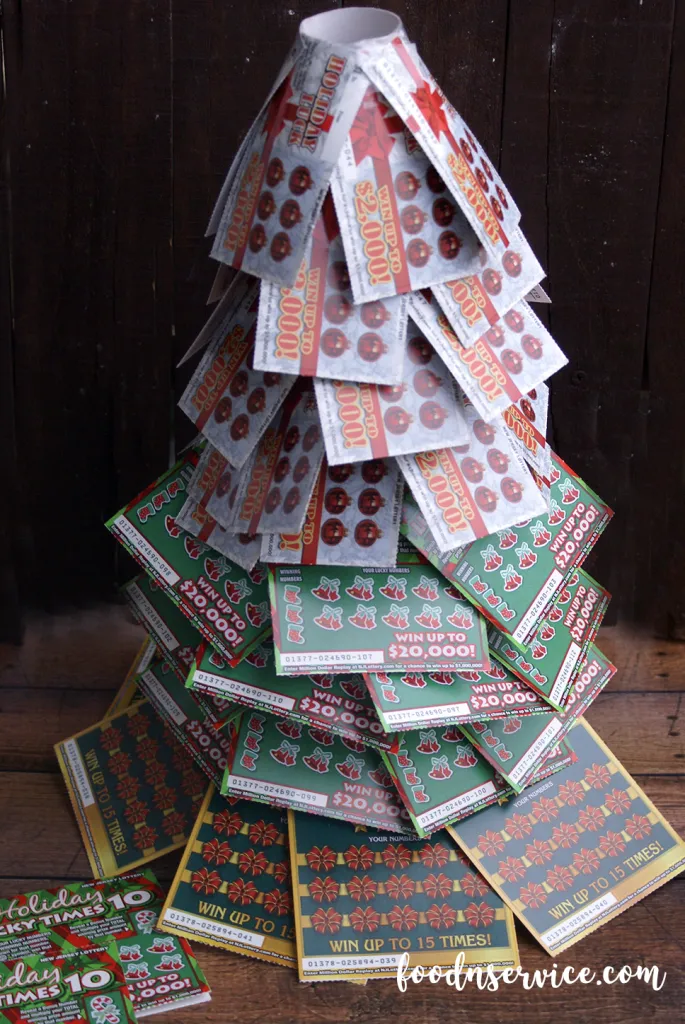 Build up the layers with the remaining $1 scratch off tickets. As you can see, I built 4 more layers with the top layer of the tree having 5. When you get to the top of the tree, you're going to want tape them down together. Once you tape them down to the top portion of the toilet paper rolls, you'll wind up getting the form of your tree! The pressure of the top layer tickets will force the others down more!