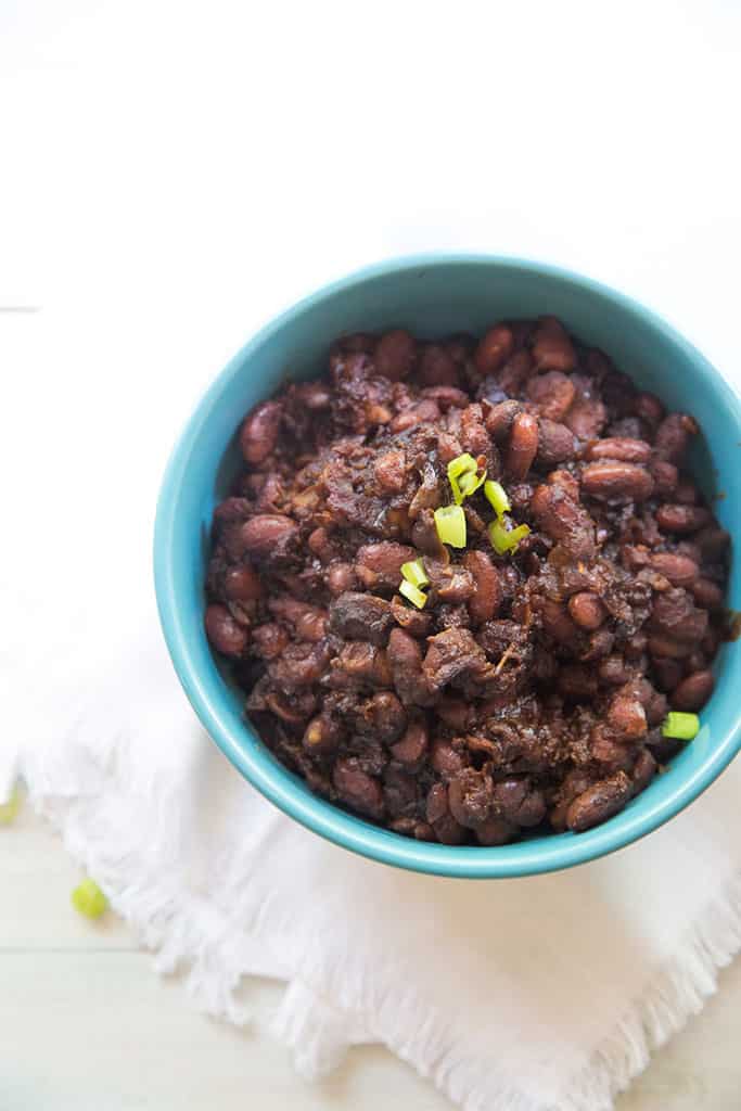 instant pot baked beans shown in a blue bowl with green onions