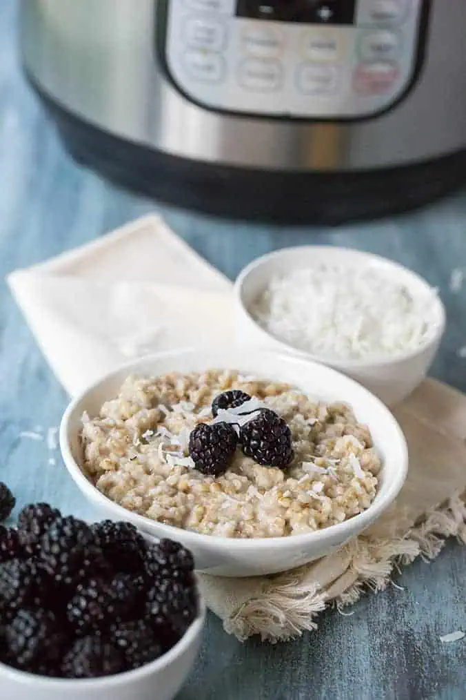 instant pot steel cut oats on a blue background with blackberries