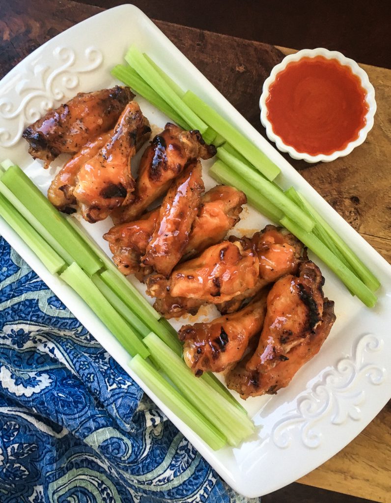 instant pot buffalo wings on a white plate with stalks of celery