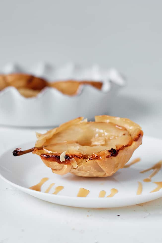 an air fryer pear tart on a white plate with a drizzle of caramel