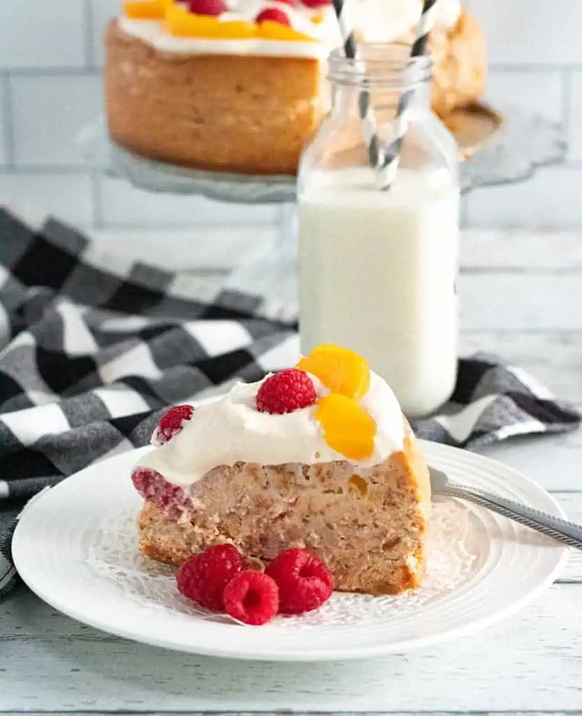 a slice of instant pot rapsberry peach cheesecake on a plate with a glass of milk