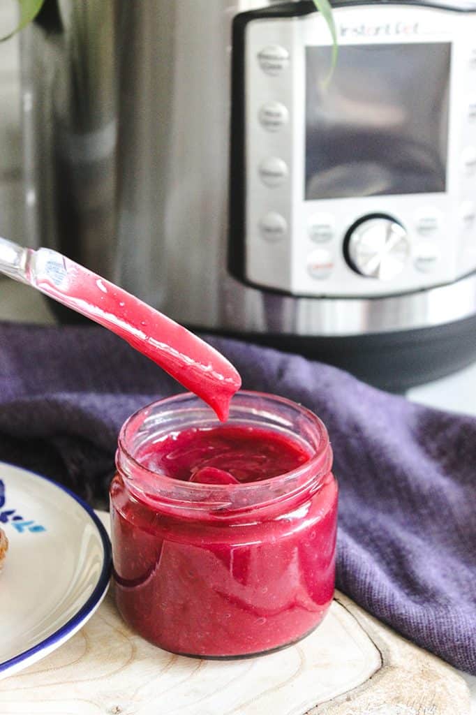 instant pot pomegranate jam in a jar and butter knife with machine in back