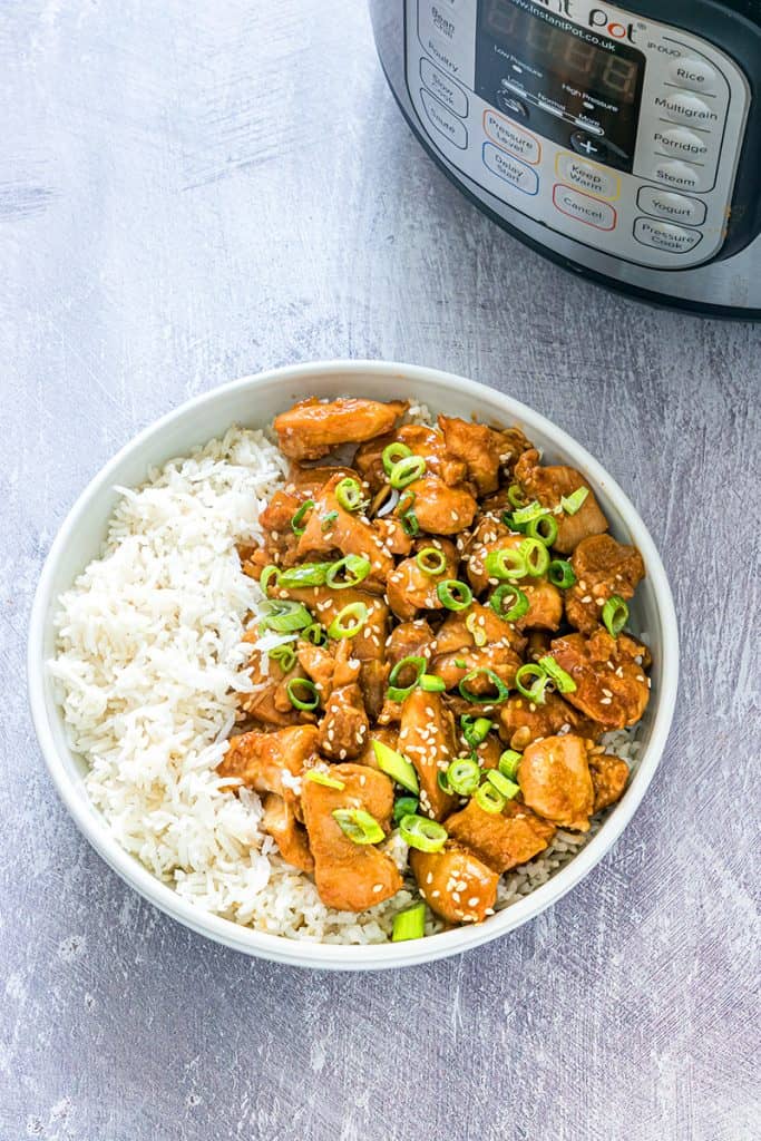 sesame chicken in a white bowl with jasmine rice next to an instant pot