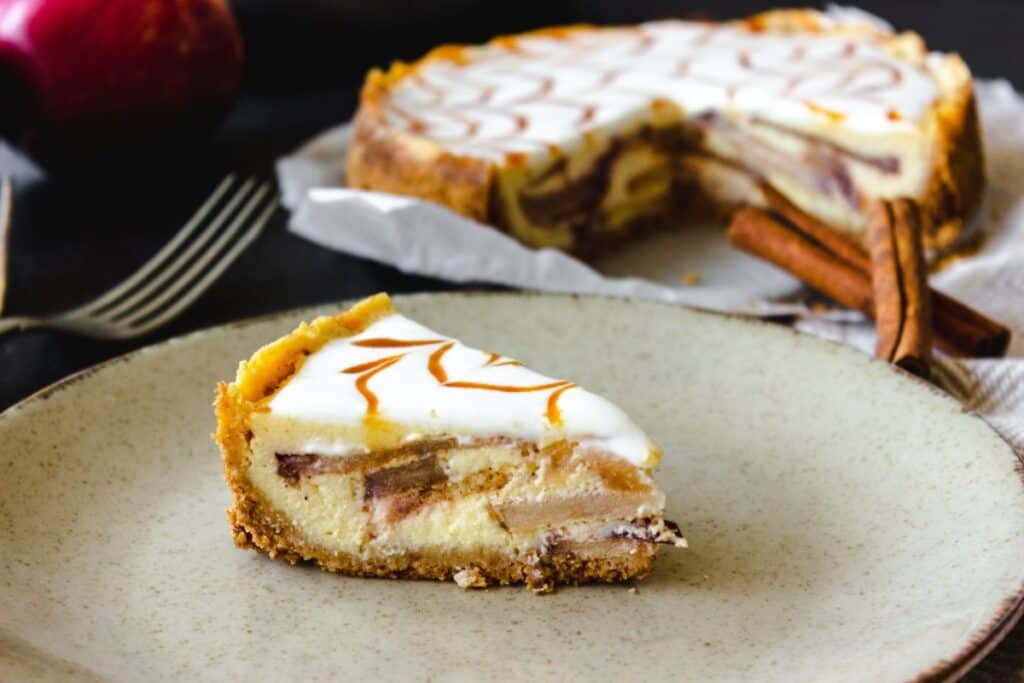 instant pot apple cheesecake as with a rustic plate and cinnamon sticks