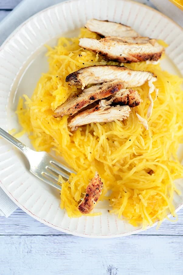 spaghetti squash with grilled chicken on a white plate