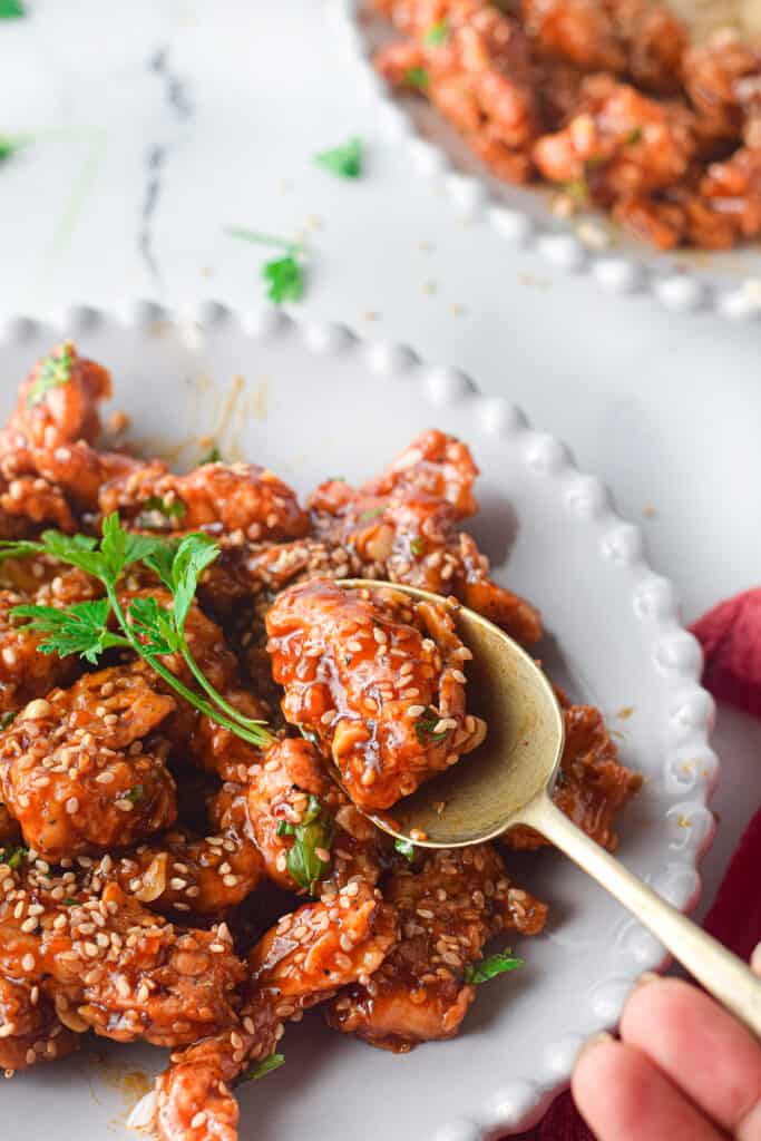 easy air fryer sesame chicken on a white plate and spoon