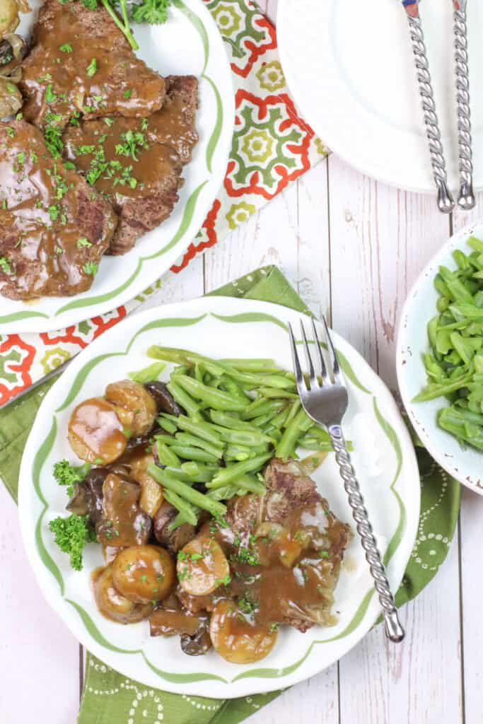 easy to make instant pot cube steak recipe on a white green plate with green beans
