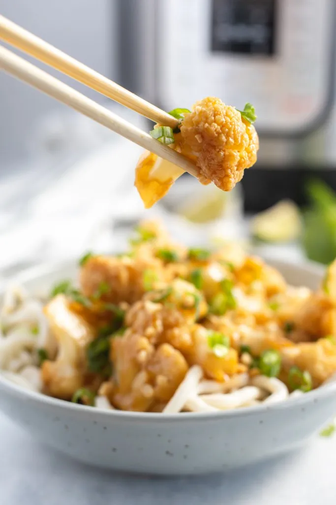 chopsticks holding instant pot kung pao cauliflower