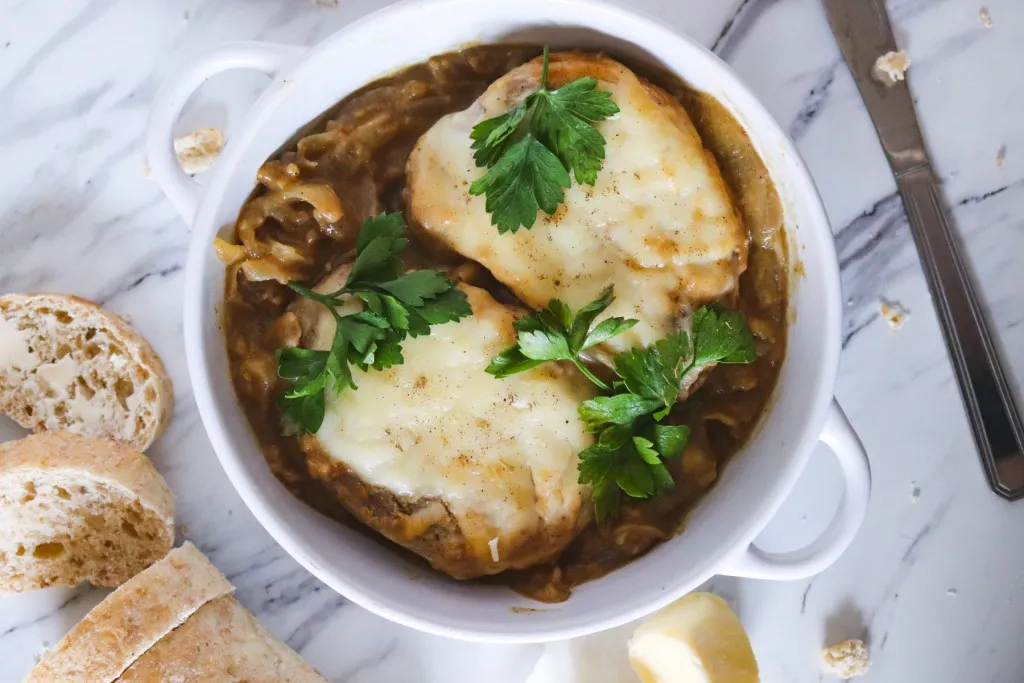 french onion porkchops with sliced bread on a marble background 