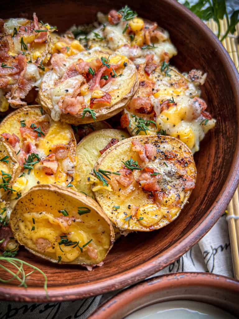 bacon and cheese topped baked potato slices with fresh herbs