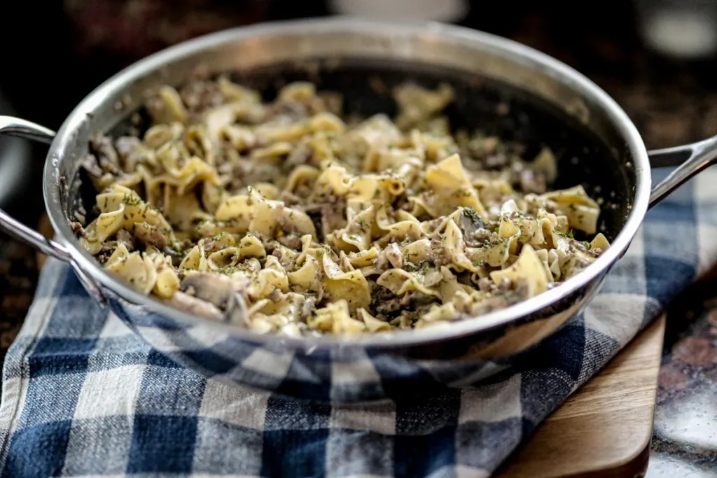 noodles, beef, and mushrooms in a sauce pan