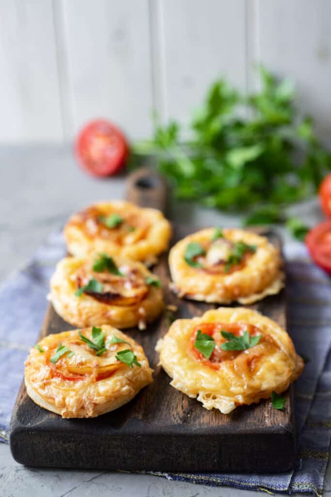 the best vegetarian puff pastry tomato tarts on a wooden cutting board